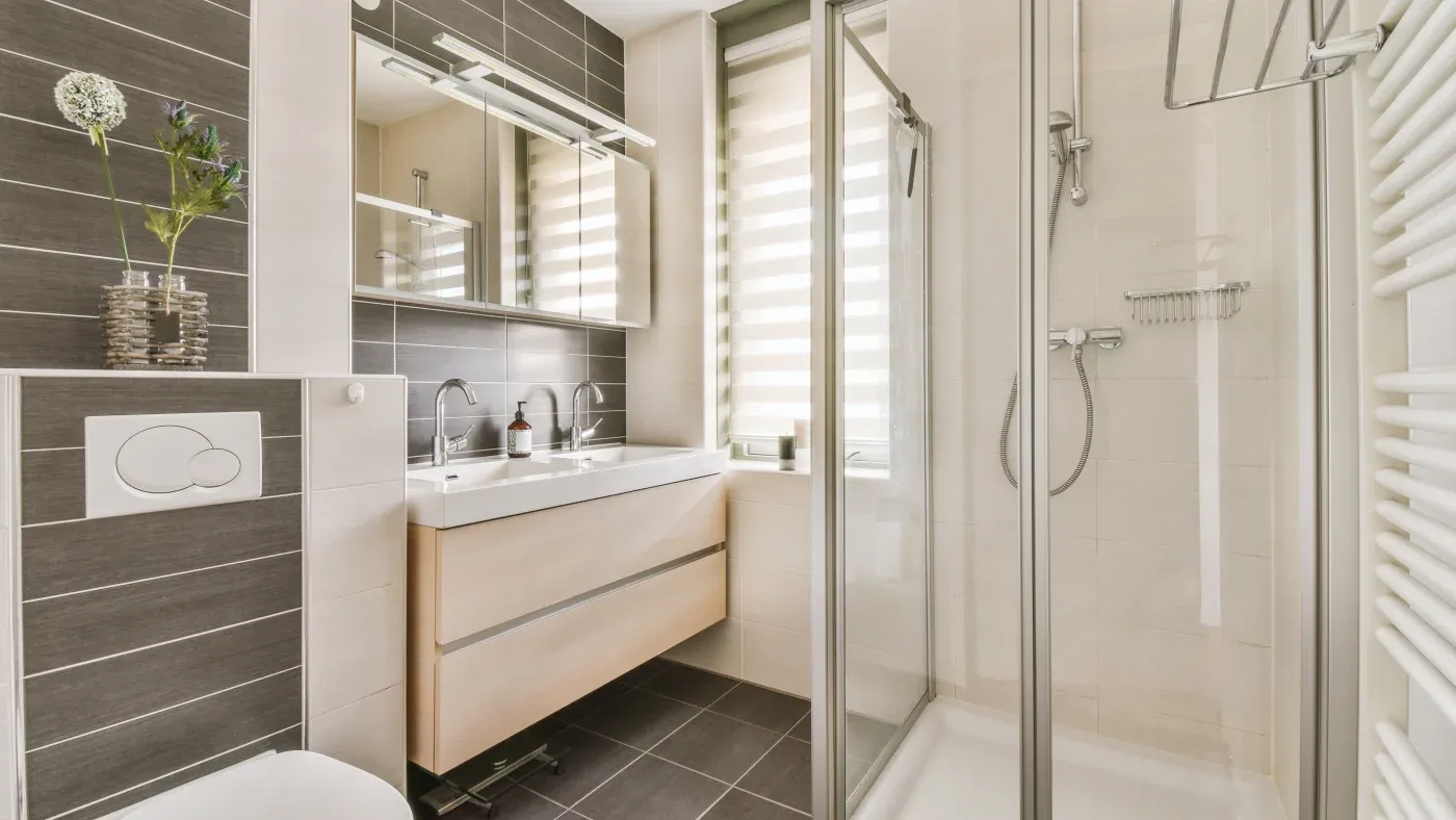 A bathroom with a walk-in shower, glass shower doors, and a vanity