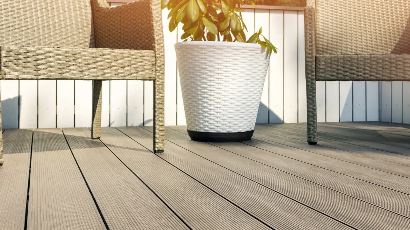 A brown deck with a white planter and brown chairs