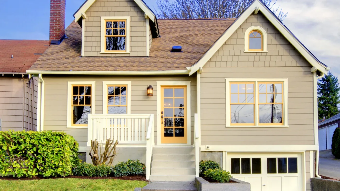 A home with gray siding, white and orange trim, and a brown roof