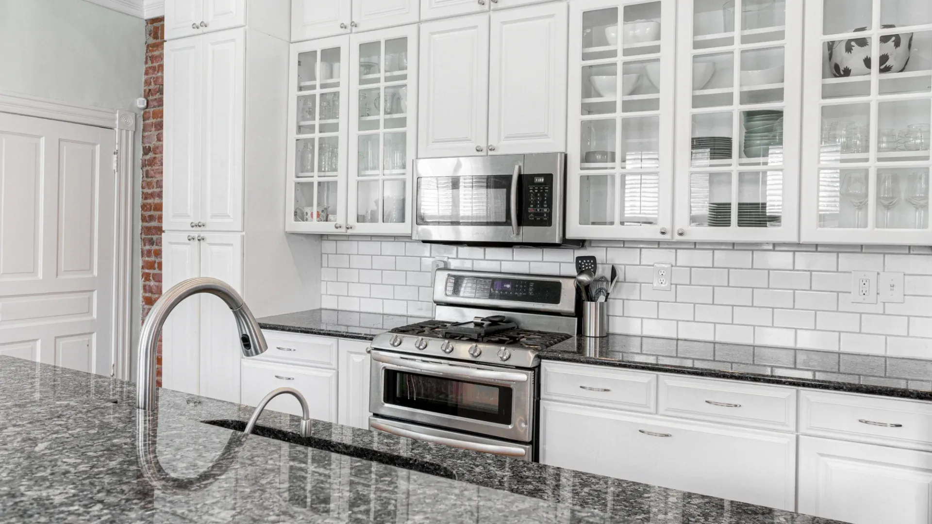 A kitchen with a white backsplash, white cabinets, and white countertops