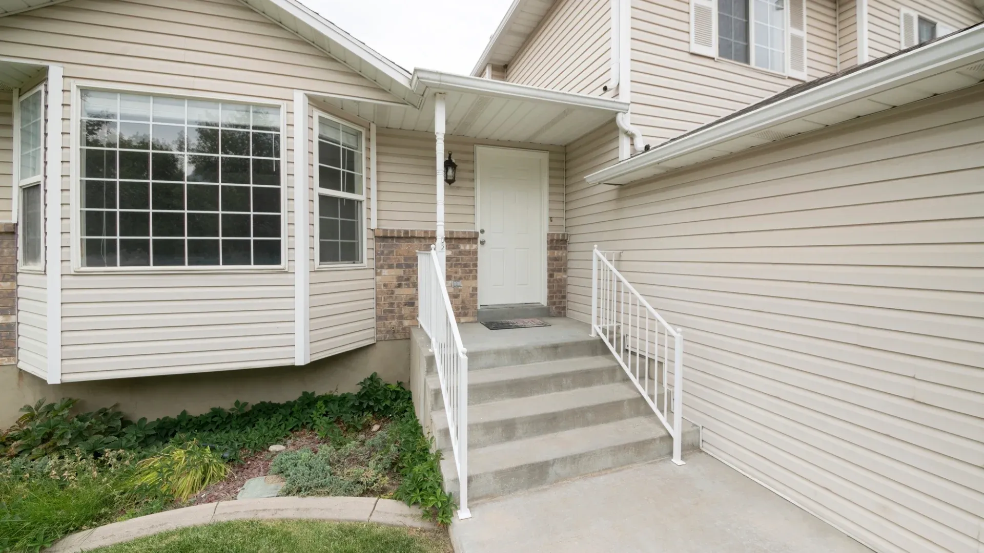 Exterior of a cream-colored home with a white front door and large front window