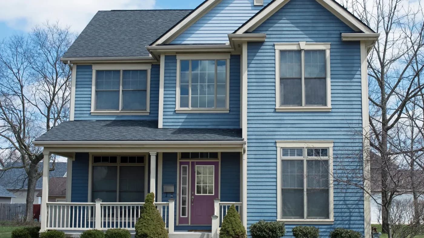 A blue home with beige trim and a black roof