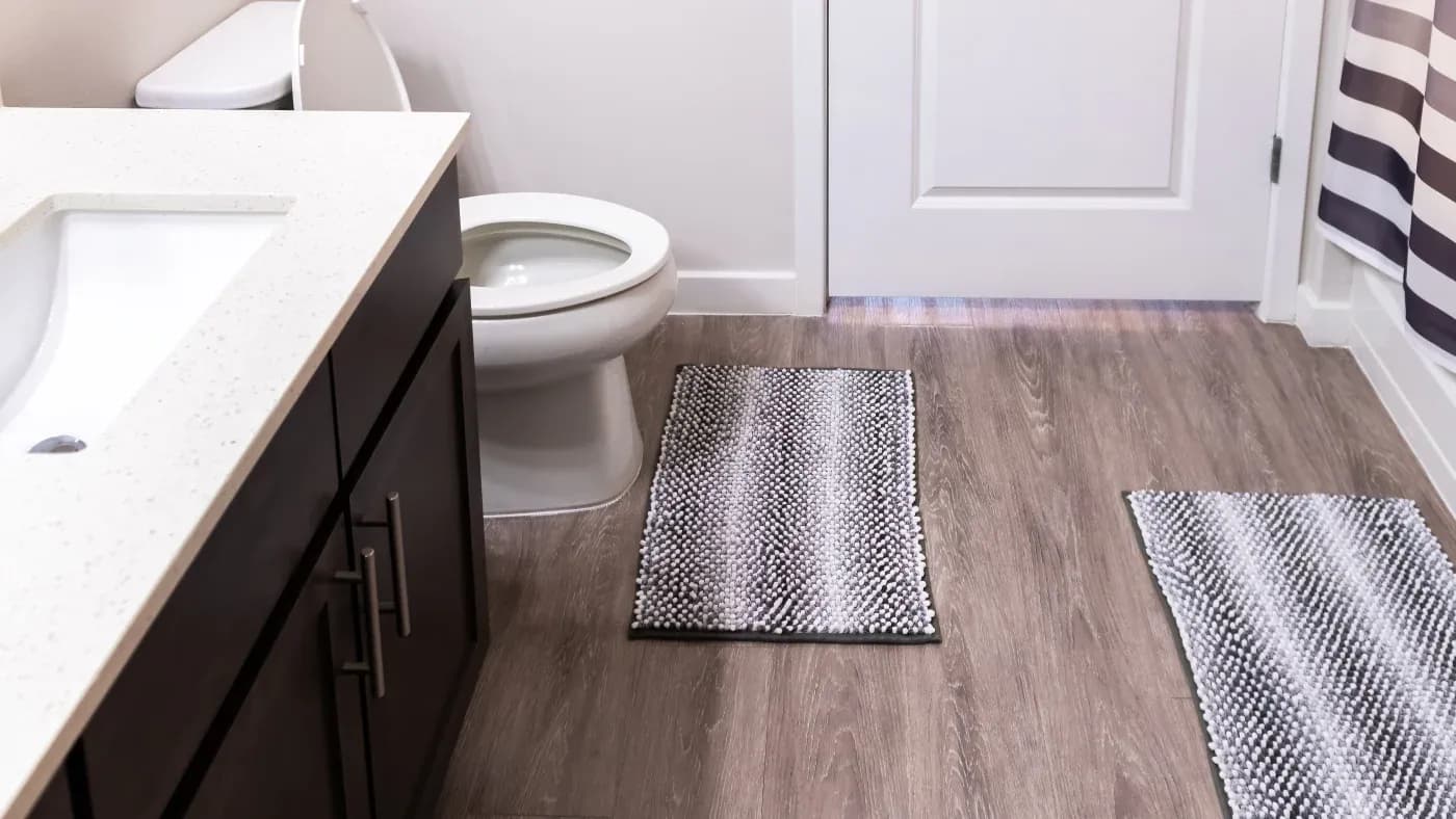 A bathroom with a black and white vanity, a brown floor, and white toilet