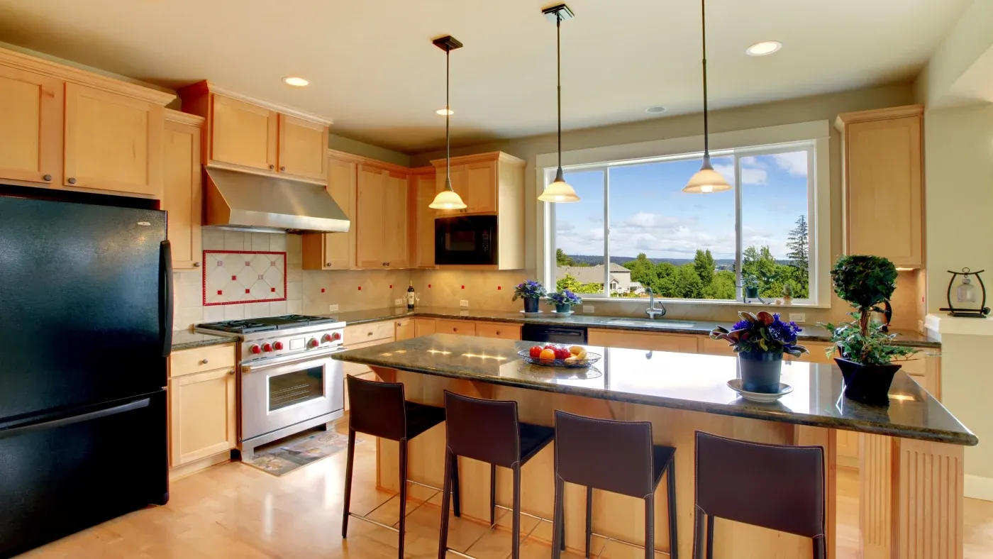 A kitchen with a large island, brown cabinets, and silver appliances