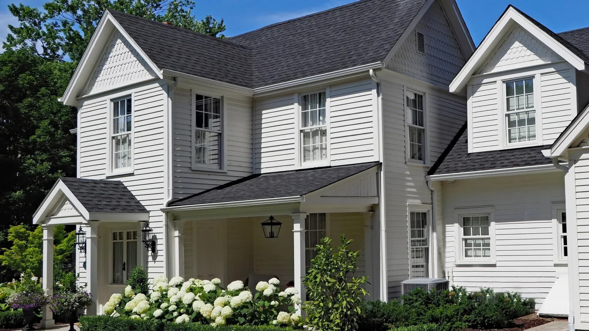 A two-story home with white siding and a gray shingle roof