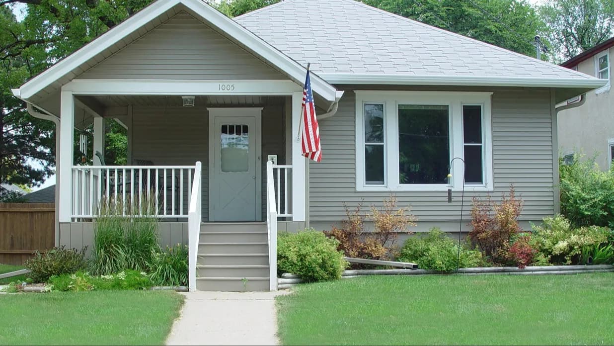 A home with light beige siding and white windows with white trim
