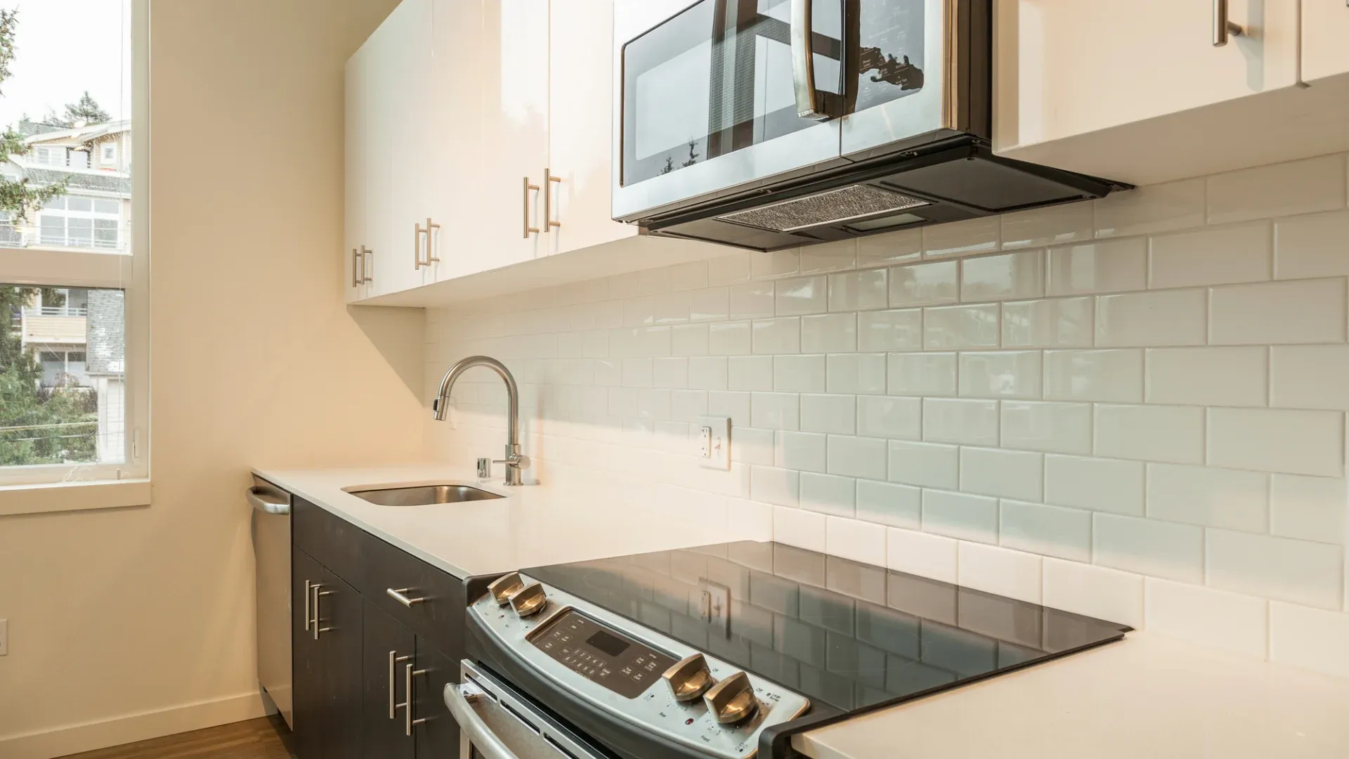 A kitchen with white cabinets and black and silver fixtures