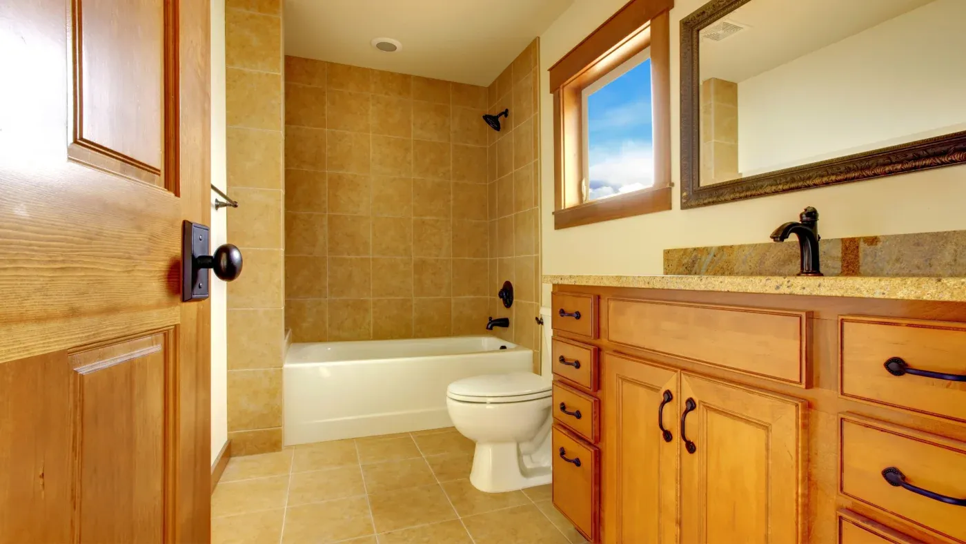 A bathroom with brown tile and a brown vanity