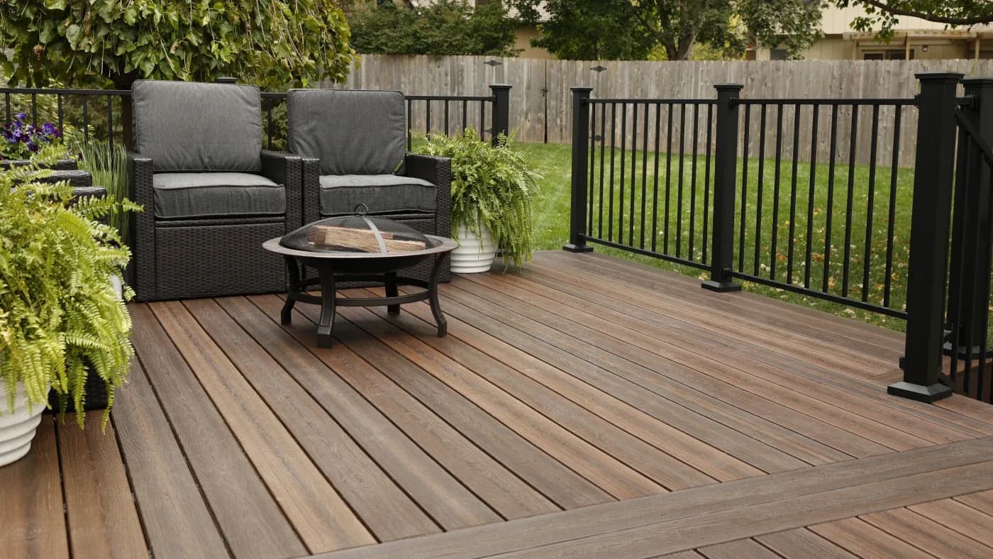 A large brown deck with black railings and gray chairs