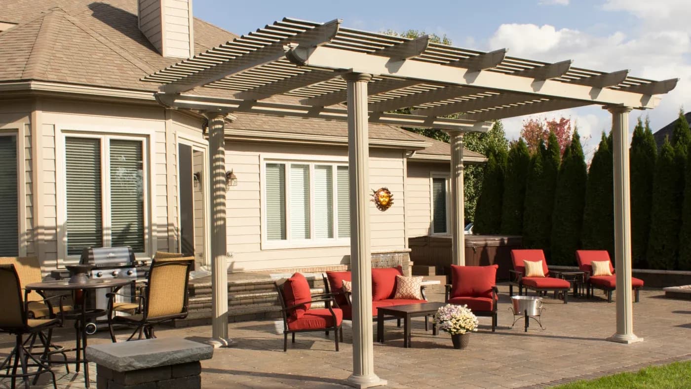 A white pergola over a patio with red furniture