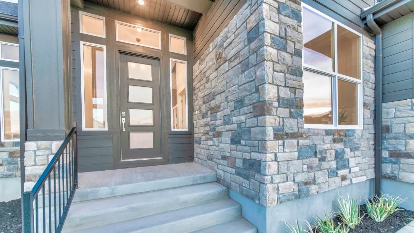 Entryway of house with stone siding, tan door, and tan trim