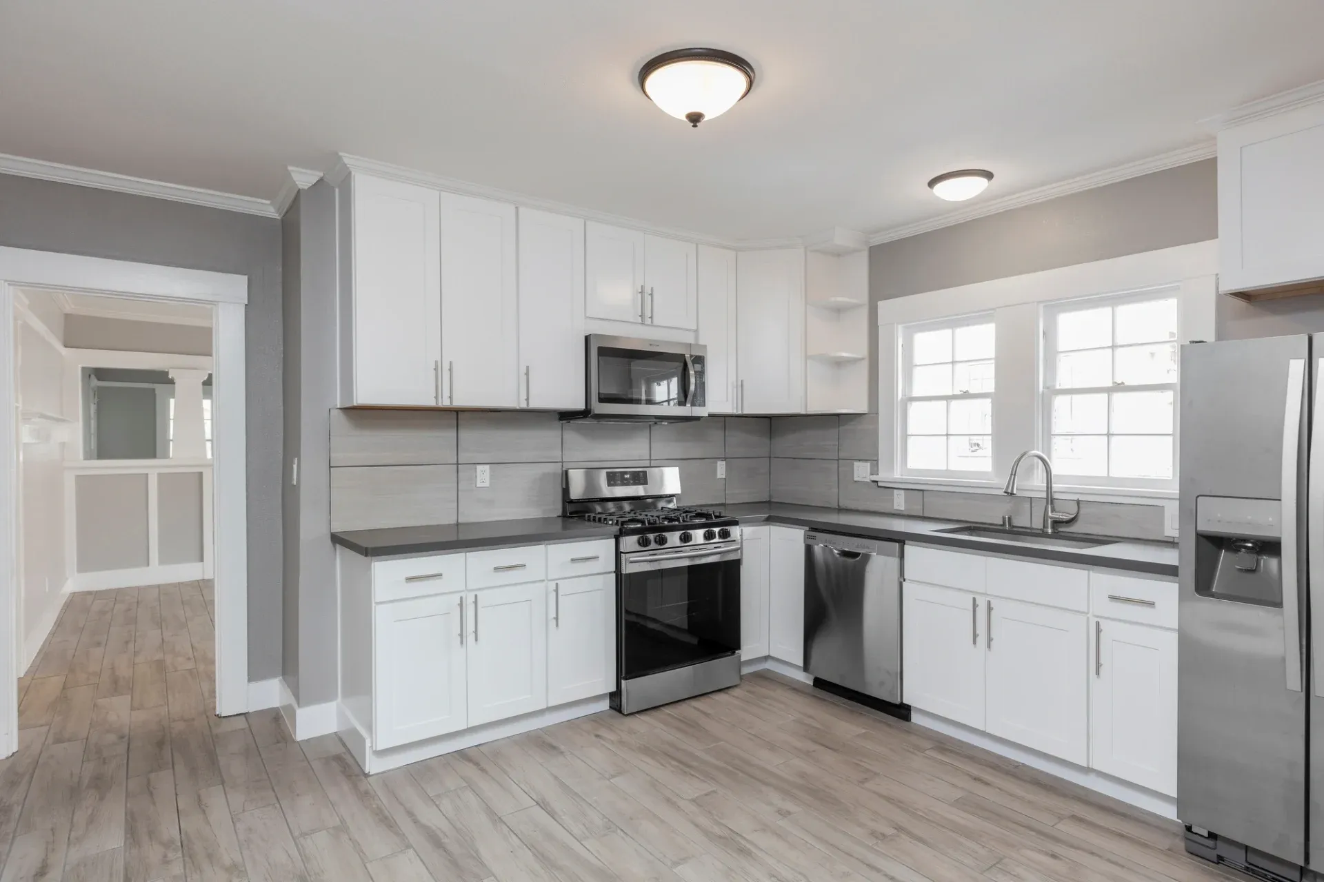 A kitchen with white cabinets, gray countertops, and stainless steel appliances