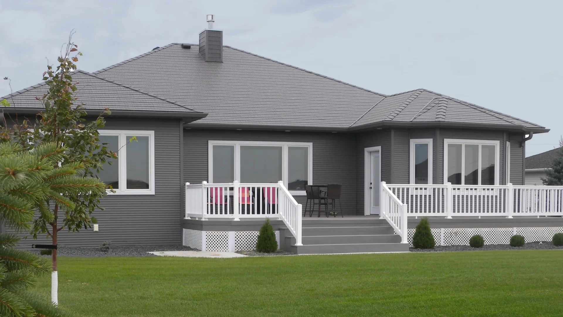 A home with dark gray siding and a deck with white railings