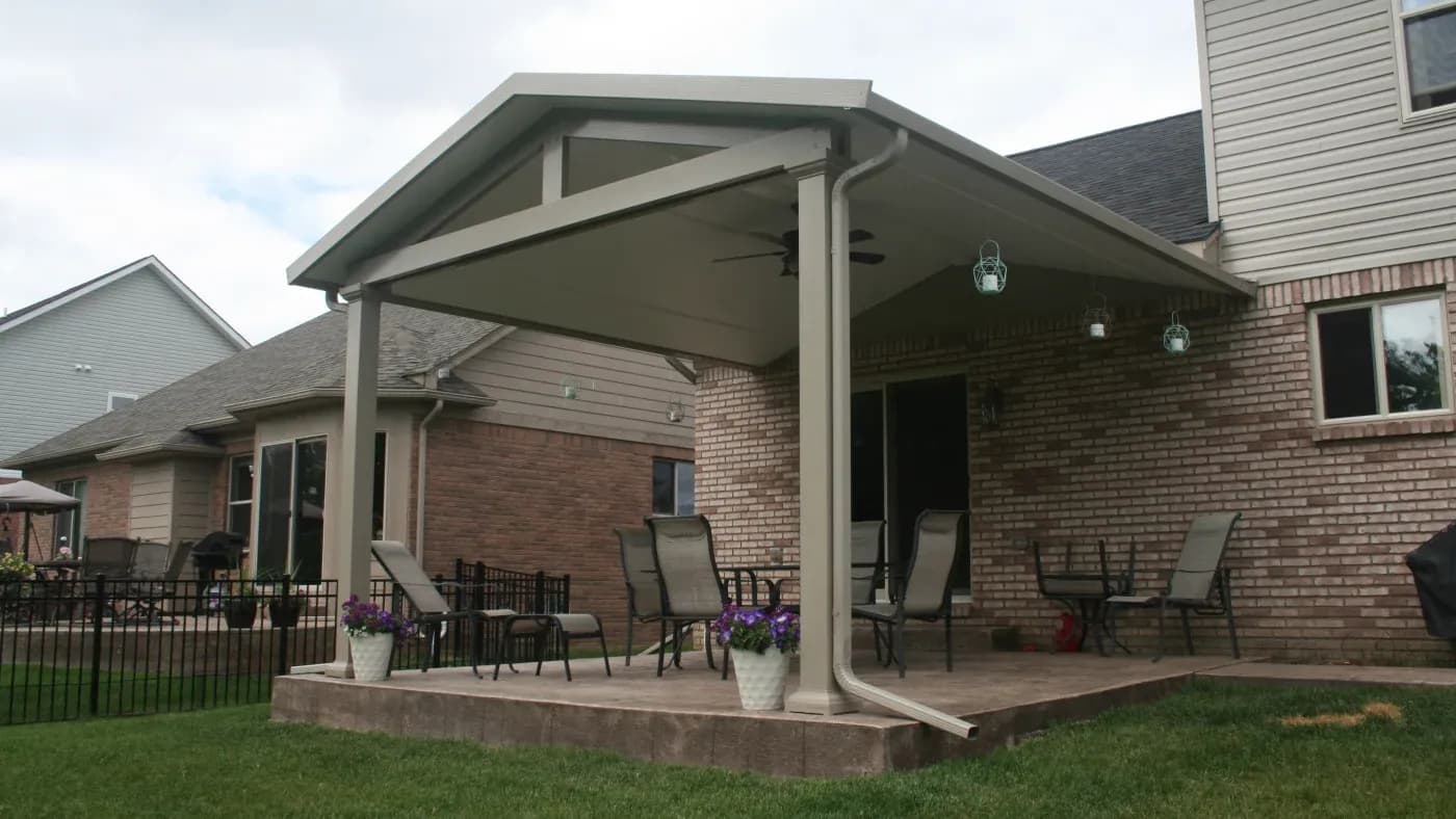 A white patio cover in a brick home with patio furniture